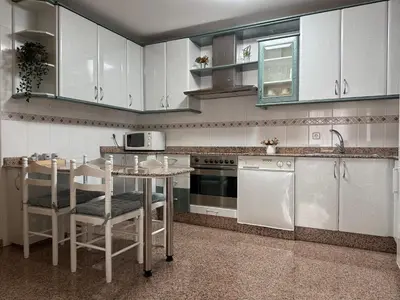a kitchen with white cabinets and a table with chairs at BierzINN Alojamientos - Martina II in Ponferrada