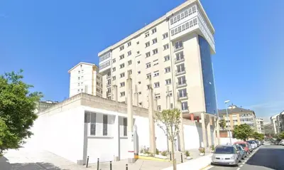 a large white building with cars parked in front of it at Estudio panorámico in Lugo