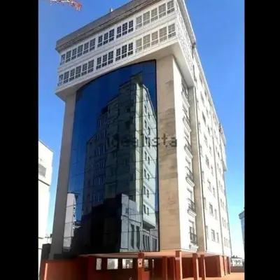 a tall building with a reflection of a building at Estudio panorámico in Lugo
