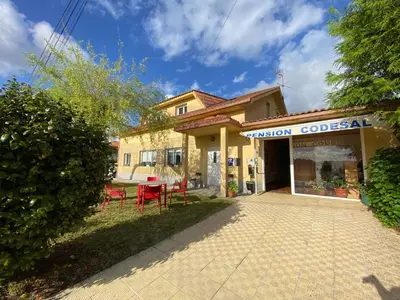 a building with a table and chairs in front of it at Pensión Codesal in O Pedrouzo