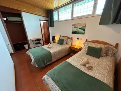 a bedroom with two beds and two windows at Pensión Codesal in O Pedrouzo