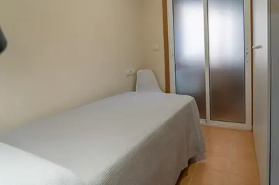 a white bed in a room with a window at Apartamento cerca del centro, y la playa in Viveiro