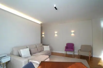 a living room with a couch and a purple chair at Apartamento nuevo y cómodo in Guitiriz