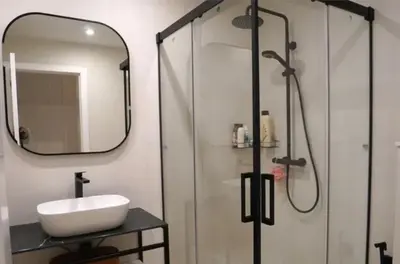 a bathroom with a sink and a shower with a mirror at Apartamento nuevo y cómodo in Guitiriz