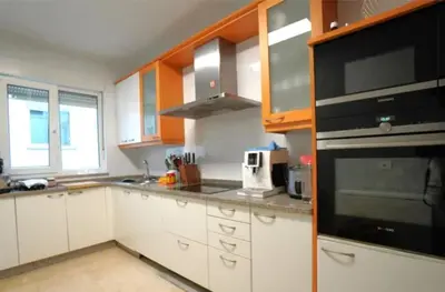 a kitchen with white cabinets and a black appliance at Apartamento nuevo y cómodo in Guitiriz