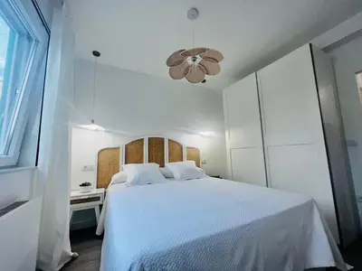 a white bedroom with a white bed and a chandelier at Villa Turquesa B in Viveiro
