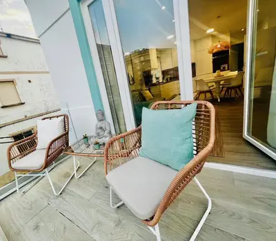 a wicker chair and a table on a porch at Villa Turquesa B in Viveiro