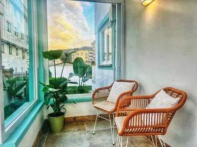 two wicker chairs sitting on a balcony with a window at Villa Turquesa B in Viveiro