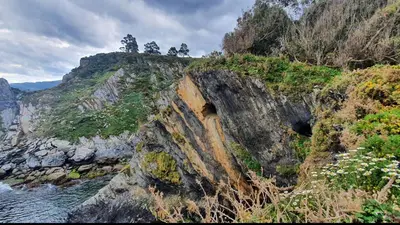 a rocky mountain with a cave in the middle of the water at Villa Turquesa B in Viveiro