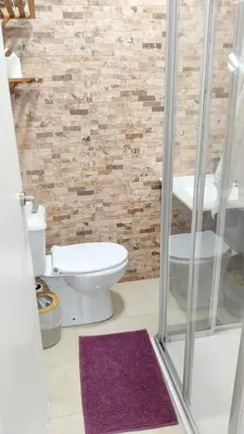 a bathroom with a toilet and a brick wall at Cuarto Antolín Yellowdoor in Ponferrada
