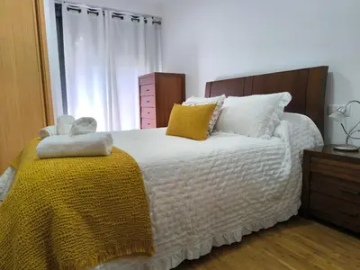 a bedroom with a white bed with a yellow blanket at Apartamento A Cañiza in La Cañiza