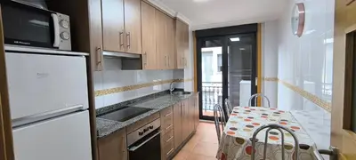 a kitchen with a white refrigerator and a table at Apartamento A Cañiza in La Cañiza