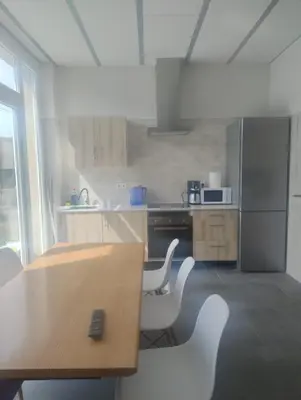 a kitchen with a wooden table and white chairs at Calm Stay in Teo