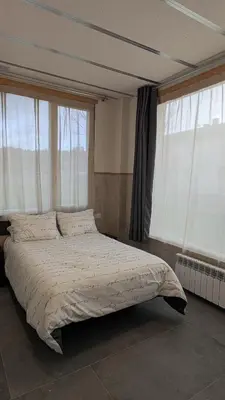 a bedroom with a large bed with windows at Calm Stay in Teo