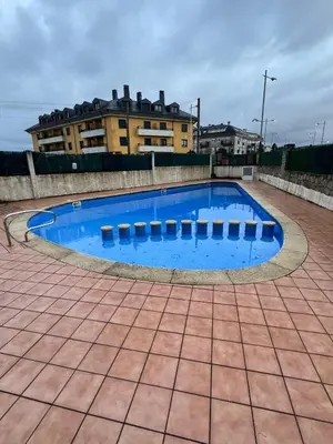 a large blue swimming pool in front of a building at Apartamento Océano VI in Villadaíde