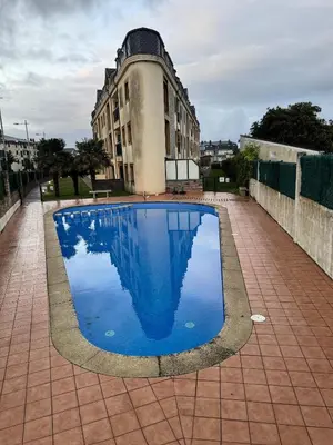 a large blue swimming pool in front of a building at Apartamento Océano VI in Villadaíde