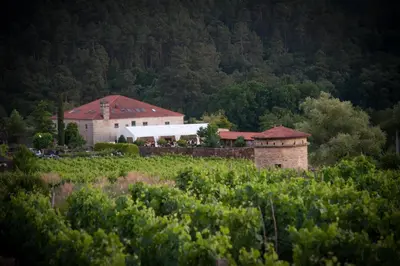 a building in the middle of a field with trees at Abadía Caldaria in Arnoia