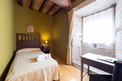 a bedroom with a bed and a desk and a window at Abadía Caldaria in Arnoia