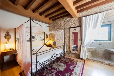 a bedroom with a metal bed in a stone wall at Abadía Caldaria in Arnoia