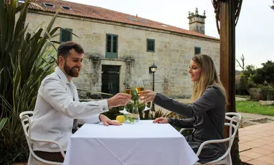 a man and woman sitting at a table with glasses of champagne at Abadía Caldaria in Arnoia