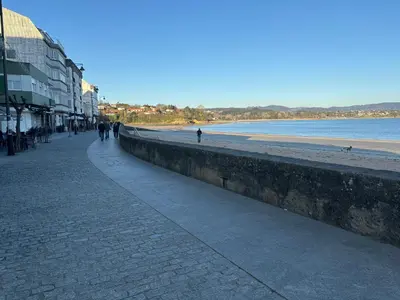 a sidewalk next to a beach with people walking on it at As Mirandas Apartment in Ares