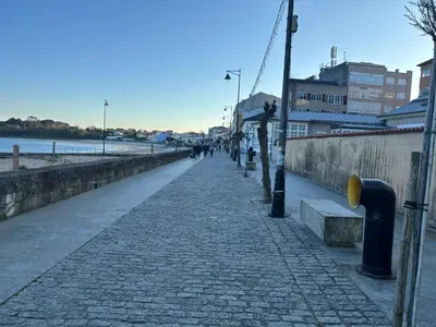 a sidewalk with people walking on it next to the water at As Mirandas Apartment in Ares
