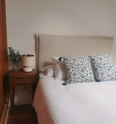 a bed with blue and white pillows and a night stand at Apartamento AIIA in Ribadeo