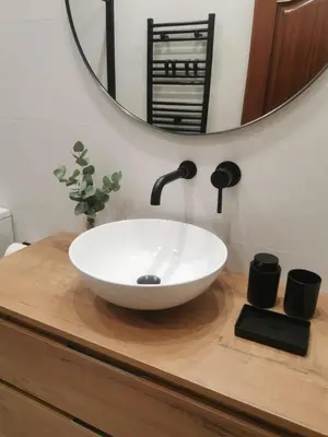 a white bowl sink on a wooden counter with a mirror at Apartamento AIIA in Ribadeo