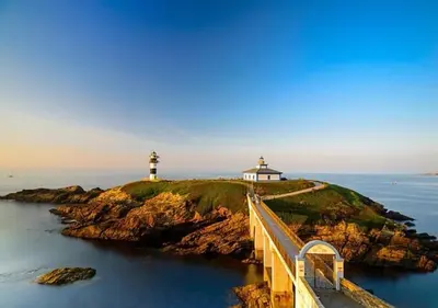a bridge leading to a lighthouse in the ocean at Apartamento AIIA in Ribadeo