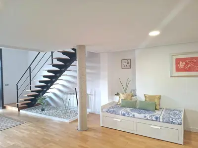 a living room with a bed and a staircase at ÁTICO CON VISTAS Centro Histórico in Allariz
