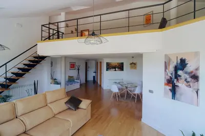 a living room with a couch and a staircase at ÁTICO CON VISTAS Centro Histórico in Allariz