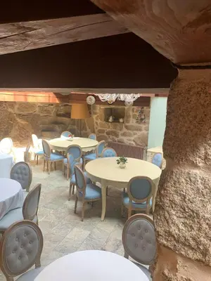 a patio with tables and chairs and a stone wall at Hotel Rústico San Jaime in Ourense