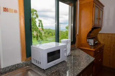 a microwave on a counter in a kitchen with a window at Cabana do Sil in Forcas