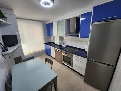 a kitchen with blue cabinets and a table and a refrigerator at SayCa CREDENCIAL in Sarria
