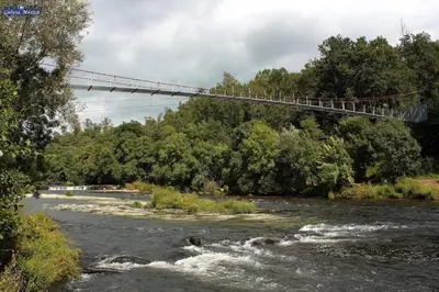 a suspension bridge over a river with rapids at Casa Trasande in Couso