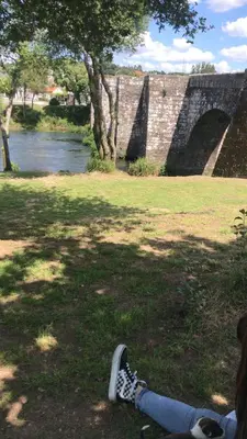 a person laying on the grass next to a bridge at Casa Trasande in Couso