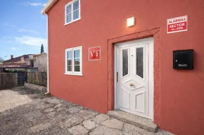 a red building with a white door and a sign at Casa Vidán completa Santiago Rural in Santiago de Compostela
