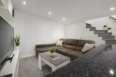 a living room with a couch and a staircase at Casa Vidán completa Santiago Rural in Santiago de Compostela