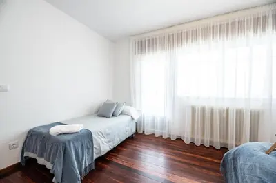 a bedroom with two beds and a large window at Atico centrico con terrazas in Monforte de Lemos
