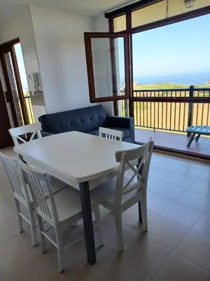 a white table and chairs in a living room with a balcony at Praia de llas in Foz