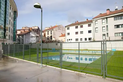 a fence with a swimming pool in a city at Apartamento Mónaco in Santiago de Compostela
