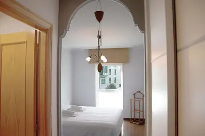 a bedroom with a white bed and a mirror at Apartamento Mónaco in Santiago de Compostela