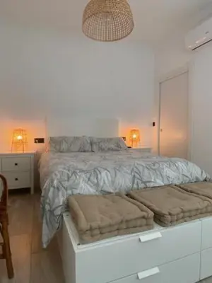 a white bedroom with a large bed and two lamps at O nido de David, un refuxio urbano na Ribeira Sacra in Monforte de Lemos