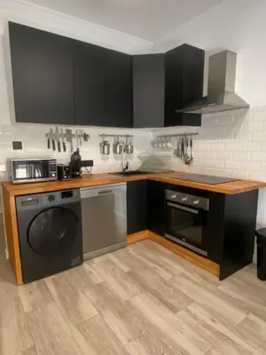 a kitchen with black cabinets and a washing machine at O nido de David, un refuxio urbano na Ribeira Sacra in Monforte de Lemos