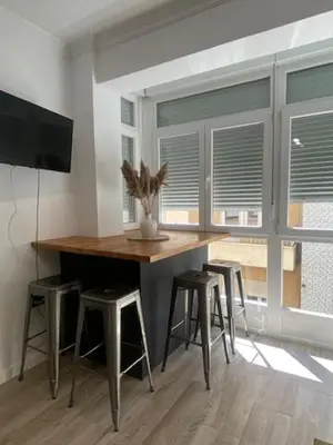 a room with a table with stools and a television at O nido de David, un refuxio urbano na Ribeira Sacra in Monforte de Lemos