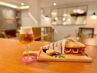 a sandwich and a glass of beer on a table at Miramar Suites in Sada