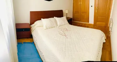 a bedroom with a white bed with a wooden headboard at apartamento céntrico y fabuloso en Ribadeo para vacaciones in Ribadeo