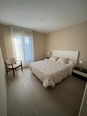 a bedroom with a bed and a chair and a window at Casa Victoriano in Melide
