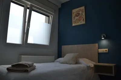 a bedroom with a bed with blue walls and two windows at Avío Apartamentos in Santiago de Compostela