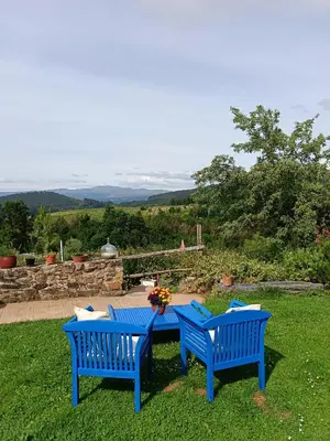 two blue benches sitting next to a table in the grass at Nuevo sabor rural Ribeira Sacra in A Pobra do Brollon